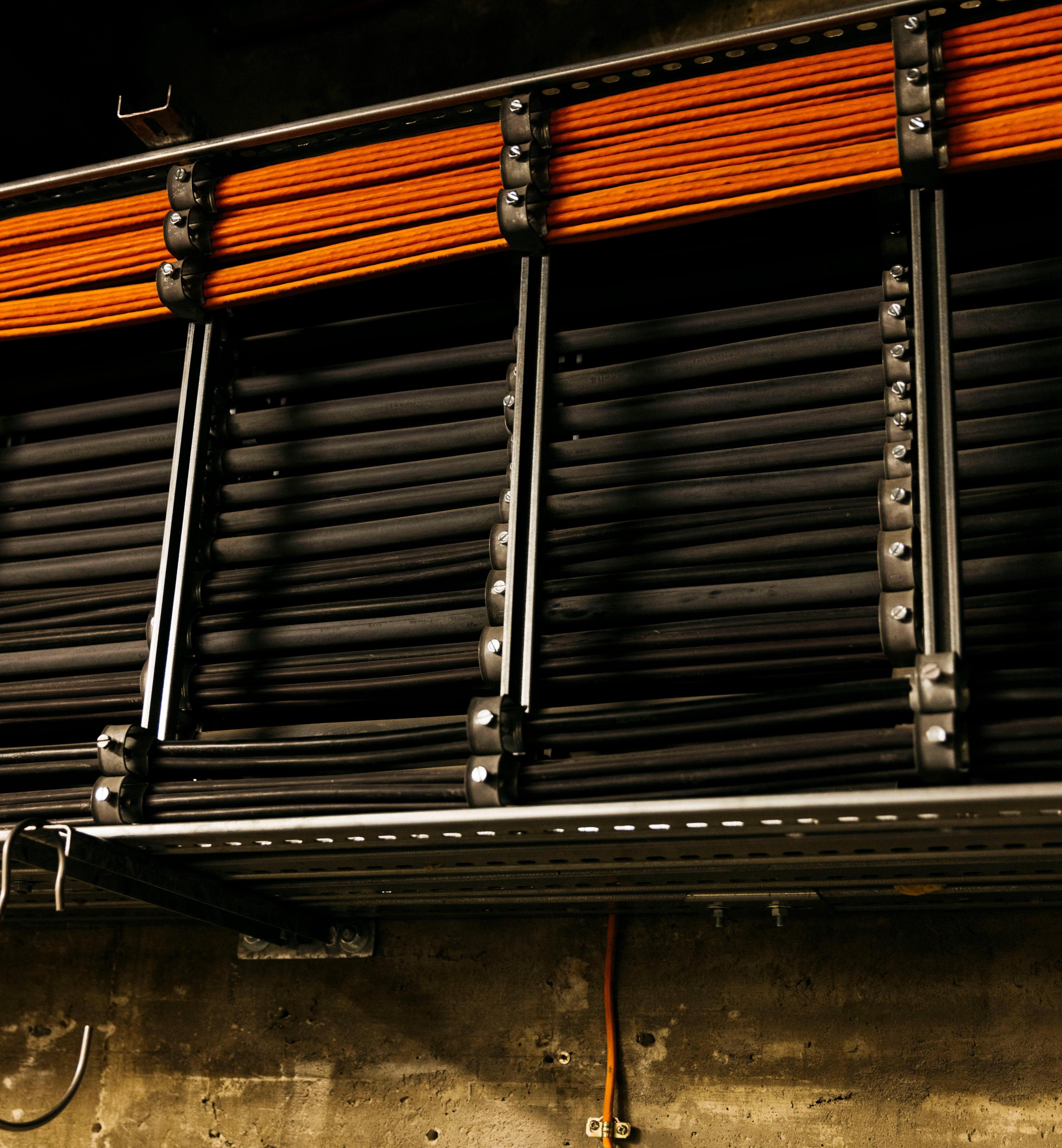 Schwarze und orangefarbene Kabel verlaufen entlang einer Wand.