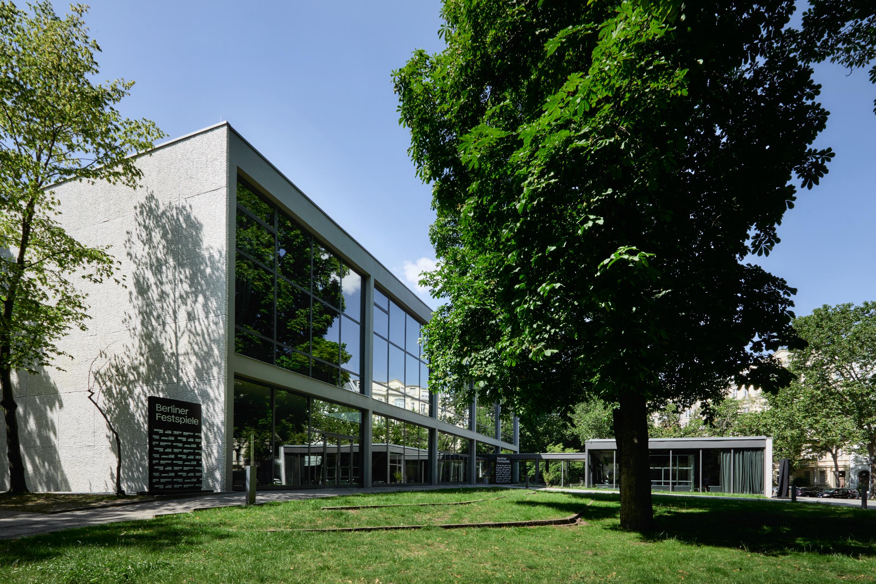 View of the Haus der Berliner Festspiele. The large glass façade of the front building can be seen.