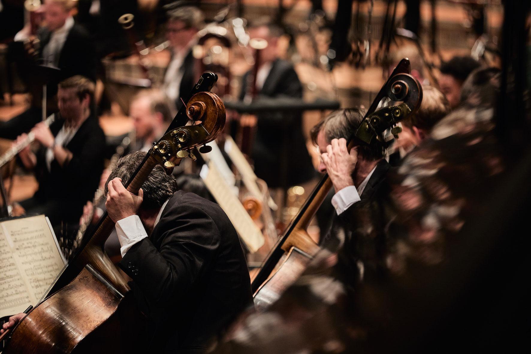 Ausschnitthafte Abbildung des London Symphony Orchestra, im Vordergrund sind zwei Cellisten vor ihren Noten erkennbar.