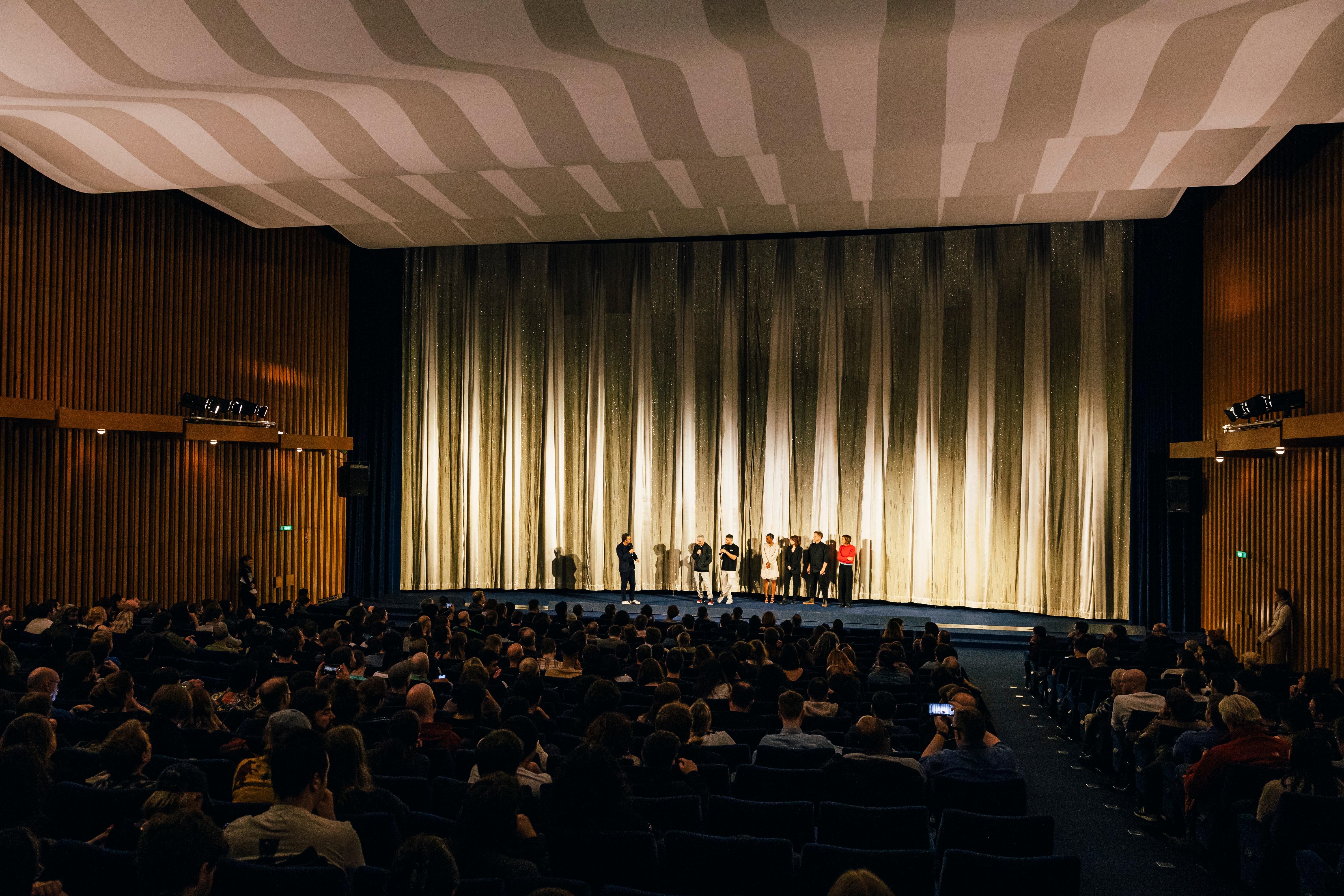 The cinema hall at Kino International with audience. On stage are the directors Danny and Michael Philippou, the actresses Alexandra Jensen and Sophie Wilde and the programmer Sergio Fant as a member of the selection committee.