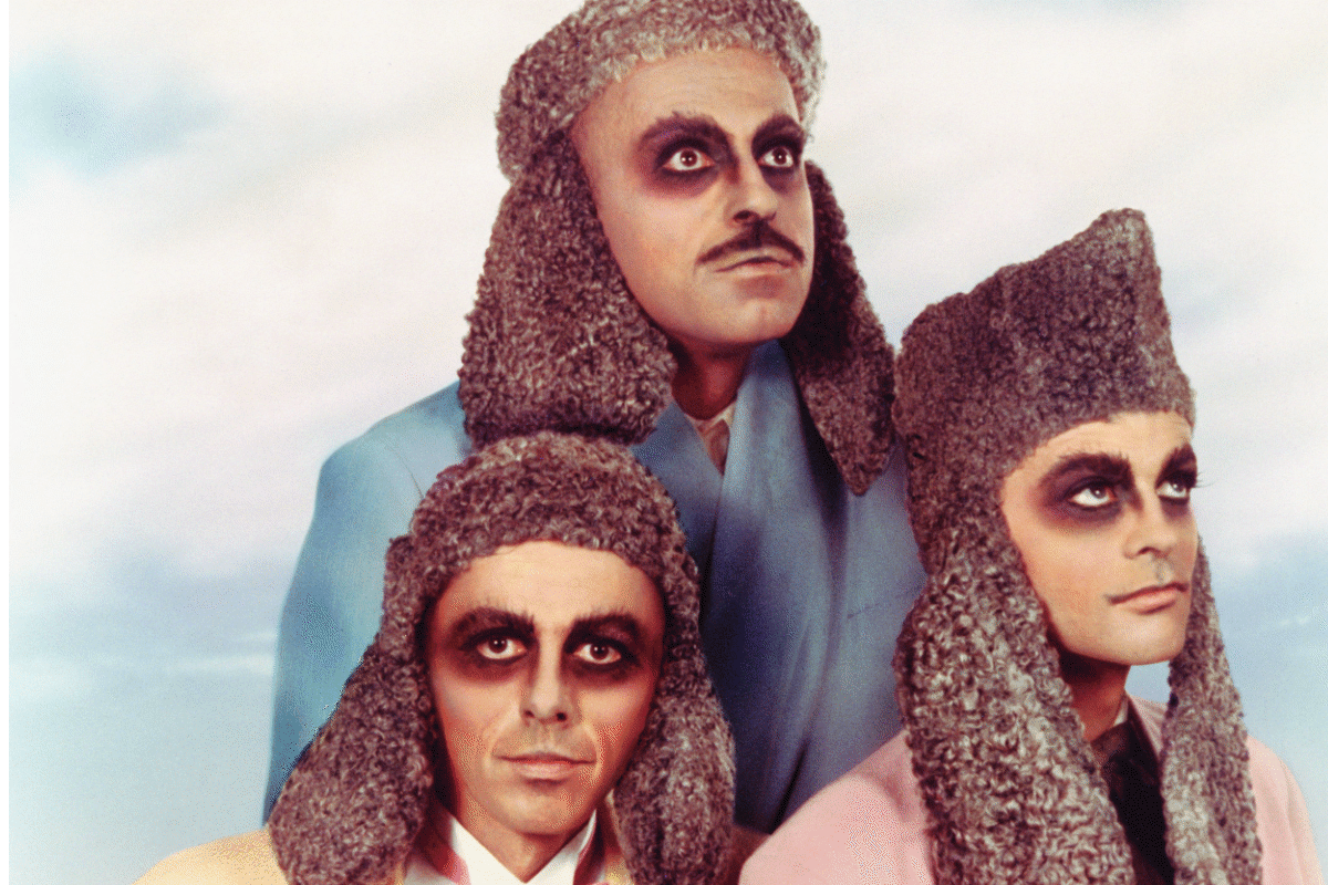 3 persons with dark make-up around the eyes, who wear caps with long earflaps.