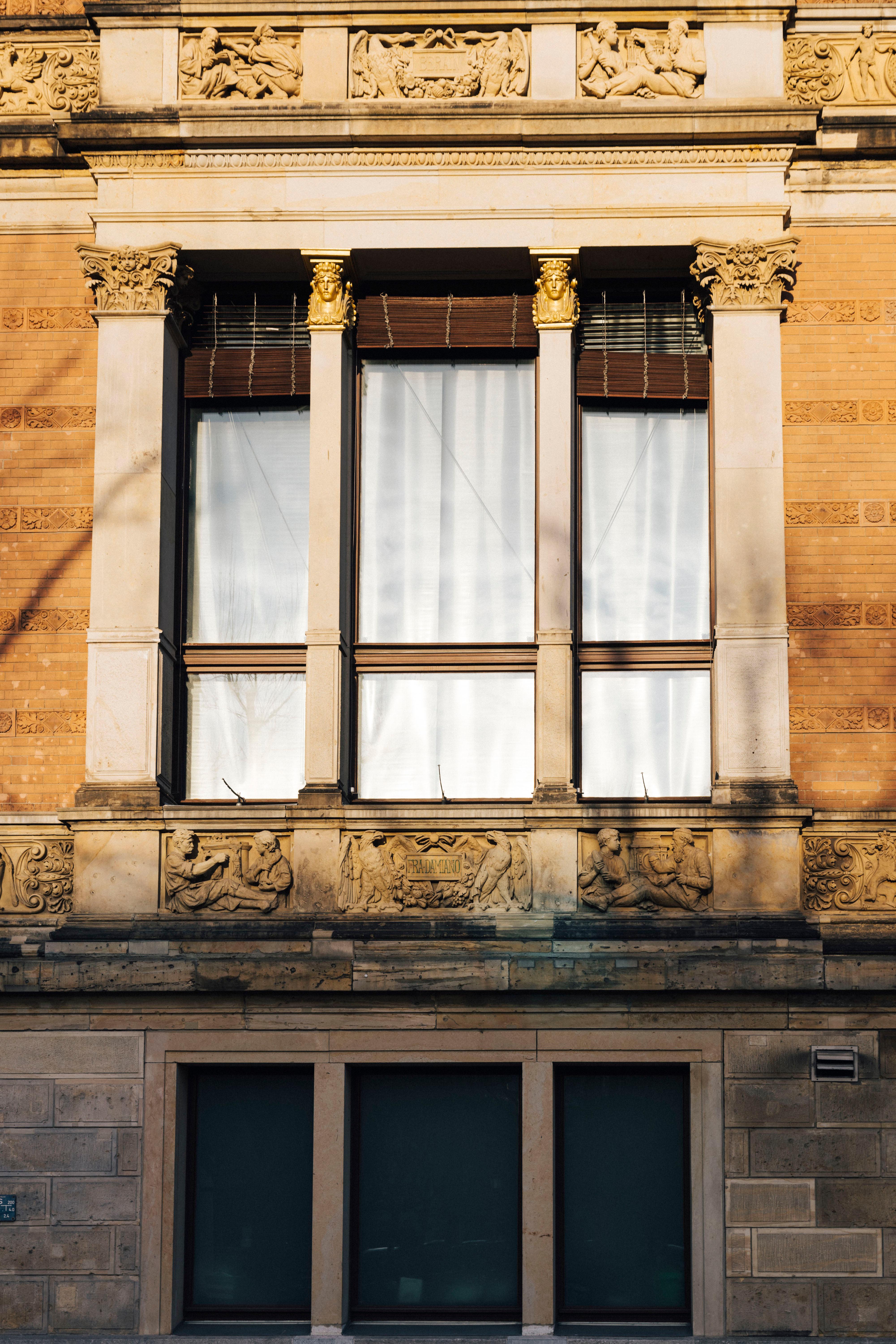 Frontalansicht auf ein Fenster des Gebäudes des Gropius Bau. Es sind gezogene weiße Vorhänge zu sehen.