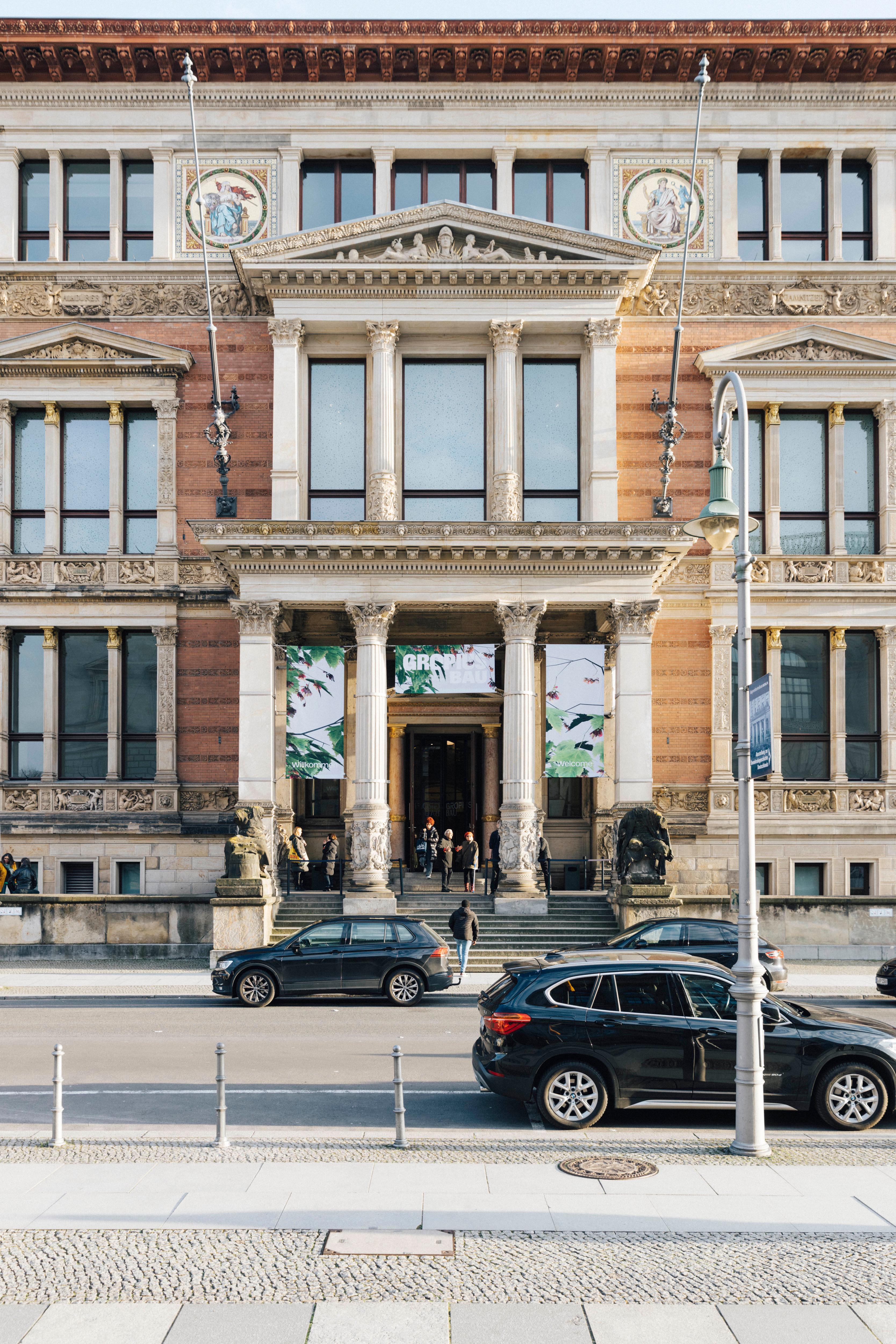 Außenansicht des Gropius Bau im Abendlicht. Besucher*innen stehen am Eingang.