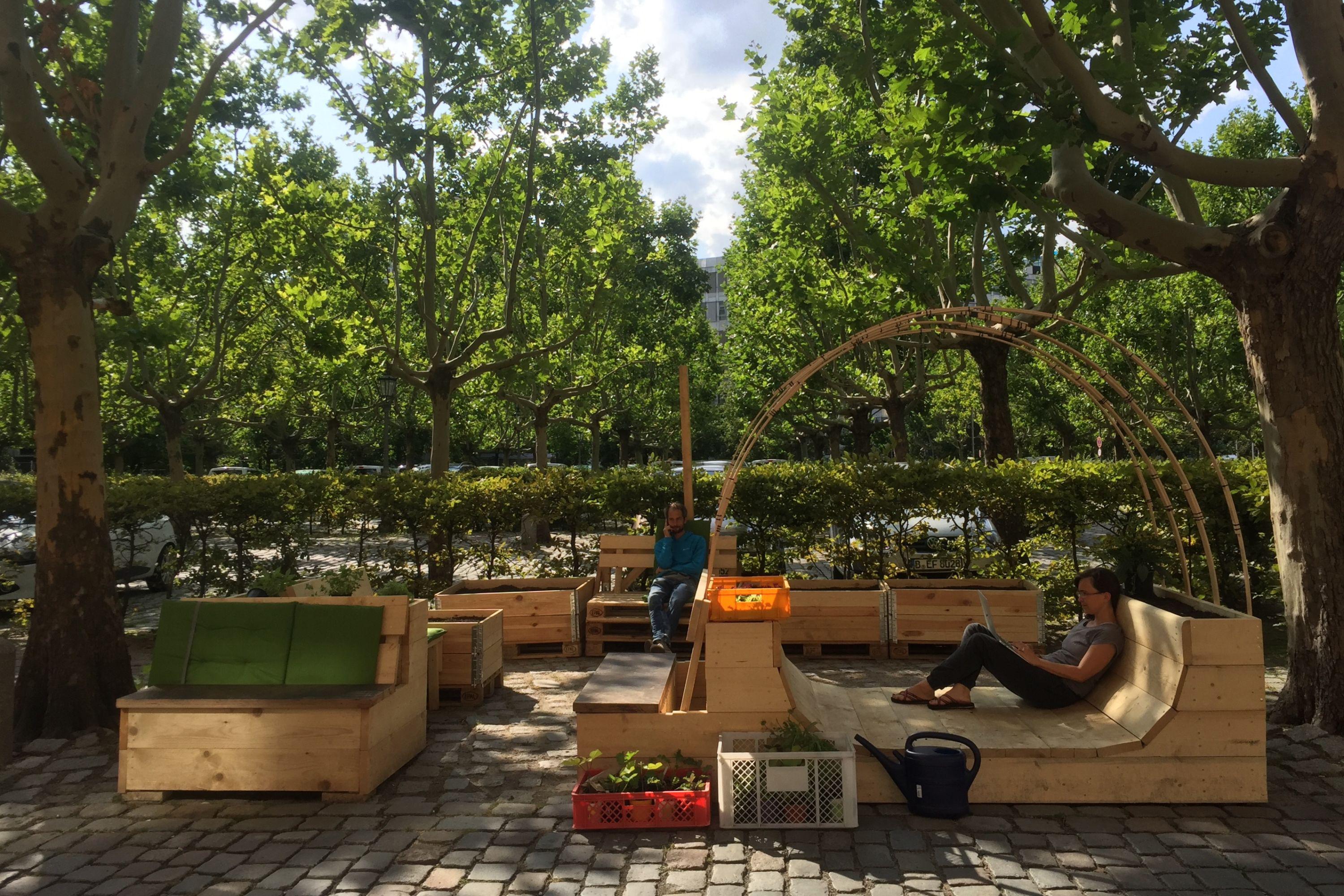 Parkplatzgarten am Gropius Bau mit Holzbänken, Liege- und Sitzmöglichkeiten sowie Pflanzenbeeten.