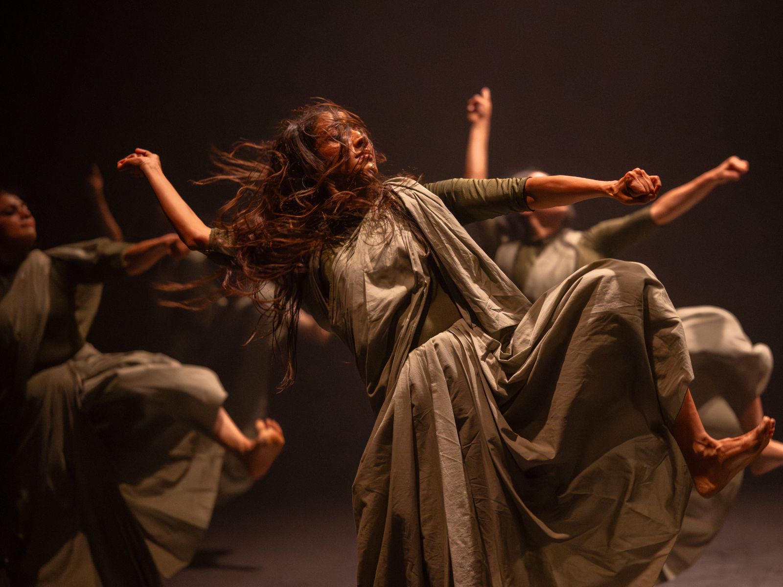 In powerful and exaggerated gestures, three performers take a step forward.