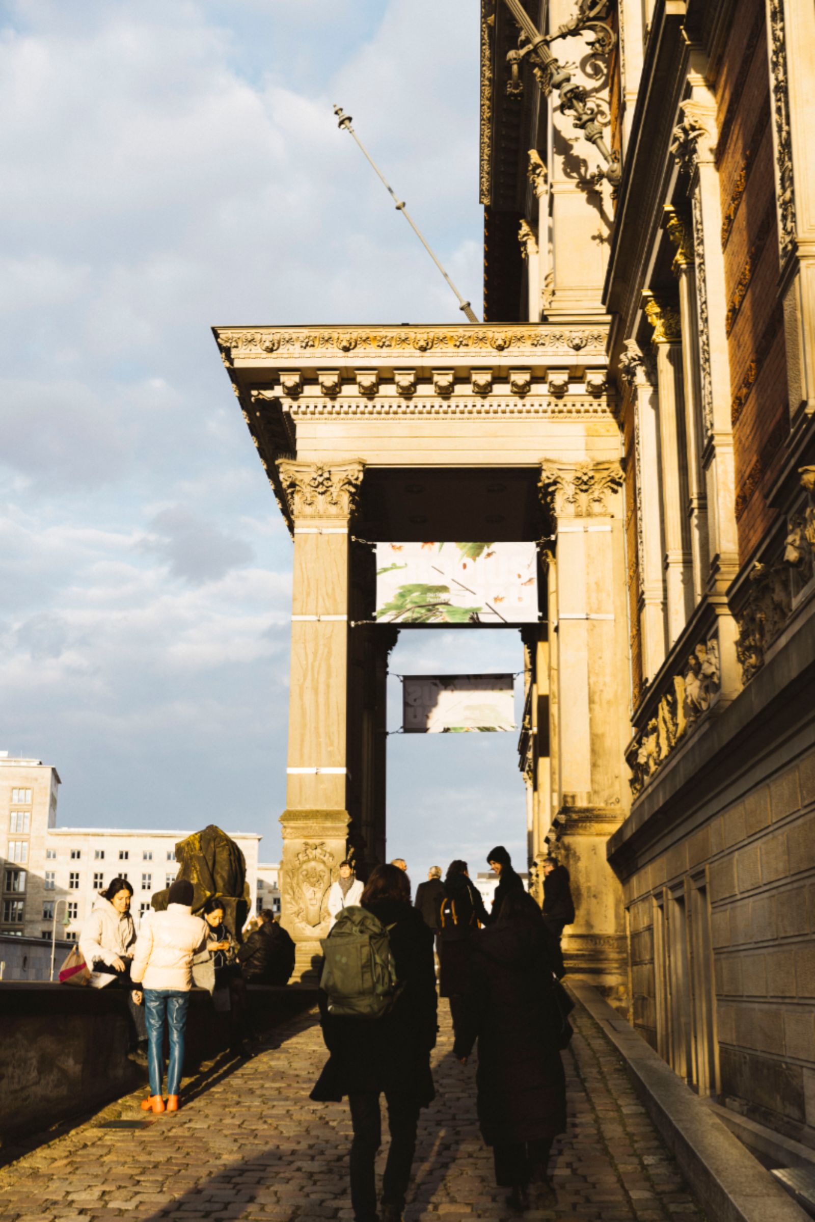Außenansicht des Gropius Bau im Abendlicht. Besucher*innen stehen am Eingang.